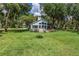 Rear view of home with lush lawn, private porch, and mature trees in a tranquil setting at 168 Pond Rd, Mount Dora, FL 32757