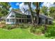 Rear exterior of a light blue home featuring a large deck, screened-in porch, pergola, and lush landscaping at 168 Pond Rd, Mount Dora, FL 32757