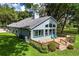 Back exterior of home featuring a deck, lush lawn, mature landscaping, and large windows at 168 Pond Rd, Mount Dora, FL 32757