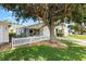 Home featuring a white picket fence, mature trees, and screened in porch at 16938 Se 94Th Sunnybrook Cir, The Villages, FL 32162