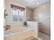 Elegant bathroom with marble tub beneath window and tiled walk-in shower at 17599 Se 121St Cir, Summerfield, FL 34491
