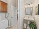 Powder room featuring a pedestal sink, decorative mirror, overhead cabinet, and an adjacent laundry room at 17599 Se 121St Cir, Summerfield, FL 34491