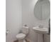 Bright half bathroom featuring pedestal sink and a round mirror at 2161 Cedar Springs Way, Minneola, FL 34715