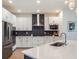 Modern kitchen with sleek white cabinetry, stainless steel appliances, and stylish black backsplash, ideal for cooking at 2161 Cedar Springs Way, Minneola, FL 34715