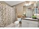 Full bathroom with floral shower curtain, decorative mirror and lighting, and ample storage at 2465 Violet Ct, The Villages, FL 32162