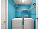 Vibrant laundry room with bright blue walls, shelving, and modern washer and dryer units at 314 Stone Castle Loop, Lady Lake, FL 32159