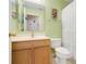 Light green bathroom with vanity, toilet, mirror, and glass shelf in front of the shower at 3213 White Blossom Ln, Clermont, FL 34711