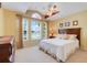 Comfortable bedroom with a queen bed, arched window, decorative fan, and neutral color scheme at 3213 White Blossom Ln, Clermont, FL 34711
