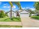 Charming single-story home with a well-maintained lawn, red front door, and a two-car garage at 3213 White Blossom Ln, Clermont, FL 34711