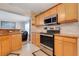 Open kitchen featuring stainless steel appliances, granite countertops, and light wood cabinets with a view to living room at 3213 White Blossom Ln, Clermont, FL 34711
