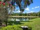 Picture-perfect backyard showcasing a serene pond, lush greenery, and clear blue skies at 4814 Saint Andrews Arc, Leesburg, FL 34748