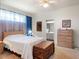 Comfortable bedroom featuring natural light, a wooden chest, an adjacent bathroom, and neutral decor at 4814 Saint Andrews Arc, Leesburg, FL 34748
