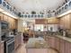 Open-concept kitchen with stainless appliances, granite countertops, and an island, flowing into the living area at 4814 Saint Andrews Arc, Leesburg, FL 34748
