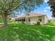 Back exterior view with screened lanai, manicured lawn, and meticulous landscaping at 487 Thistledown Way, The Villages, FL 32162