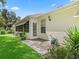 Exterior back view featuring a screened lanai, lush landscaping, and home features at 487 Thistledown Way, The Villages, FL 32162