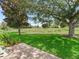 View of a lush green back yard with golf course views, mature trees, and well-maintained lawn at 487 Thistledown Way, The Villages, FL 32162
