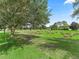 View of a lush green back yard with golf course views, mature trees, and well-maintained lawn at 487 Thistledown Way, The Villages, FL 32162