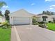 Home featuring two car garage, beautiful landscaping, and decorative driveway at 487 Thistledown Way, The Villages, FL 32162