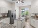 Well-lit kitchen with white cabinets, stainless steel appliances and a central island with granite countertops at 487 Thistledown Way, The Villages, FL 32162