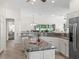 Modern kitchen with granite countertops, stainless steel appliances, and views to open living spaces at 487 Thistledown Way, The Villages, FL 32162