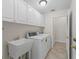 Laundry room features a washer and dryer, utility sink, and storage cabinets at 487 Thistledown Way, The Villages, FL 32162