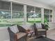 Comfortable patio featuring wicker chairs, tile flooring, and serene views of the landscaped backyard at 487 Thistledown Way, The Villages, FL 32162