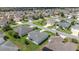 Aerial view of a community shows homes with lanais, mature landscaping, and well-manicured lawns at 516 Junction Pl, The Villages, FL 32163