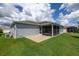 A view of the back of the house shows a screened patio with a lawn beyond the patio's edge at 516 Junction Pl, The Villages, FL 32163