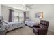 Bright bedroom with two beds, ceiling fan, area rug, window with blinds, and leather chair at 516 Junction Pl, The Villages, FL 32163
