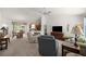 Open-concept living room with neutral carpet, ceiling fan and seamlessly connected to dining and kitchen areas at 516 Junction Pl, The Villages, FL 32163