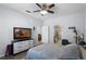 Bright bedroom with a ceiling fan, adjacent bathroom, and television at 520 Rainbow Springs Loop, Groveland, FL 34736