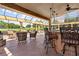 Covered patio features a bar with stools, pendant lighting, and outdoor seating area at 5235 Greens Dr, Lady Lake, FL 32159