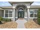 Charming front entrance with an arched doorway, gray stone walkway, and well-manicured landscaping, creating a welcoming curb appeal at 5412 County Road 125, Wildwood, FL 34785