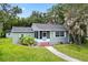 Charming single-story home featuring a screened-in porch and landscaped front yard with mature trees at 601 S 12Th St, Leesburg, FL 34748