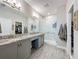 Modern bathroom with dual vanity, granite countertops, a glass-enclosed shower, and wood-look tile flooring at 655 Conservation Blvd, Groveland, FL 34736