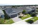 Aerial view of a gray single-story home featuring a manicured lawn, landscaping, and brick driveway at 655 Conservation Blvd, Groveland, FL 34736