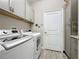 Functional laundry room with modern washer and dryer, ample cabinet space, and stylish tile flooring at 655 Conservation Blvd, Groveland, FL 34736