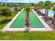 Aerial view of community bocce ball court surrounded by mature landscaping and lush green lawns at 8128 Penrose Pl, Wildwood, FL 34785