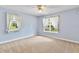 Light-filled bedroom with soft blue walls, carpet, ceiling fan, and bright windows with decorative curtains at 9223 Silver Lake Dr, Leesburg, FL 34788