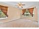 This light-filled bedroom features neutral walls, carpet, ceiling fan, and windows with attractive curtains at 9223 Silver Lake Dr, Leesburg, FL 34788