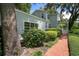 Landscaped side yard with brick path leading to a covered porch, surrounded by lush greenery and mature trees at 9223 Silver Lake Dr, Leesburg, FL 34788