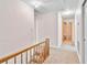 Carpeted hallway featuring an oak-colored cabinet, attic access, and natural light at 9223 Silver Lake Dr, Leesburg, FL 34788