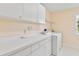 Bright laundry room offers ample counter and cabinet space, washer, dryer, and a window for natural light at 9223 Silver Lake Dr, Leesburg, FL 34788