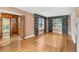 An open living room featuring beautiful hardwood floors, large windows with decorative curtains, and open access to an adjacent room at 9223 Silver Lake Dr, Leesburg, FL 34788