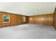 Spacious living room featuring wood-paneled walls and two windows, offering ample natural light at 9223 Silver Lake Dr, Leesburg, FL 34788