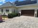 Attached garage with dark wood doors, solar panels, and a paver driveway at 10301 Savannah Ridge Ln, Winter Garden, FL 34787