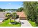 Scenic aerial view of a single-story home near a tranquil lake, lush trees, and green lawns at 1032 Ventura Dr, Lady Lake, FL 32159