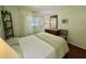 Cozy bedroom showcasing neutral decor, a dresser with mirror, and a window with sheer curtains for soft lighting at 113 Temple W Cv, Leesburg, FL 34748