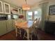 Bright dining area with wooden table and chairs, large windows, and adjacent kitchen with ample cabinet space at 113 Temple W Cv, Leesburg, FL 34748