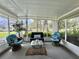 Inviting screened-in porch with ample natural light and relaxing wicker furniture arrangement at 113 Temple W Cv, Leesburg, FL 34748